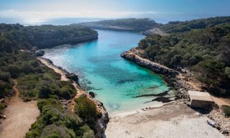 Foto aérea de Cala Sa Nau desde la arena visualizando su meandro hasta el mar