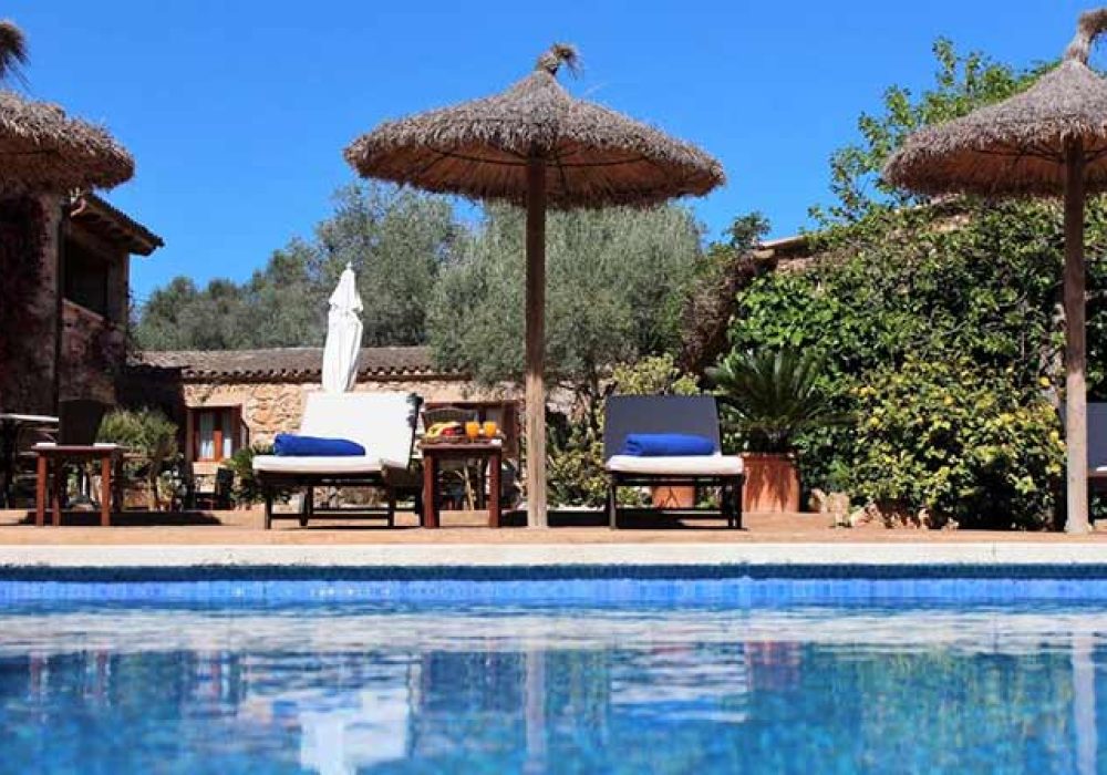 Zona de piscinas, tumbonas y sombrillas en Finca Es Torrent